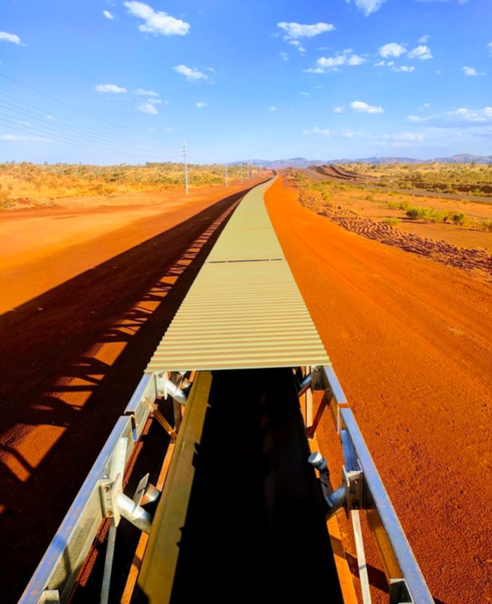 Overland conveyor extending across a remote red-earth landscape